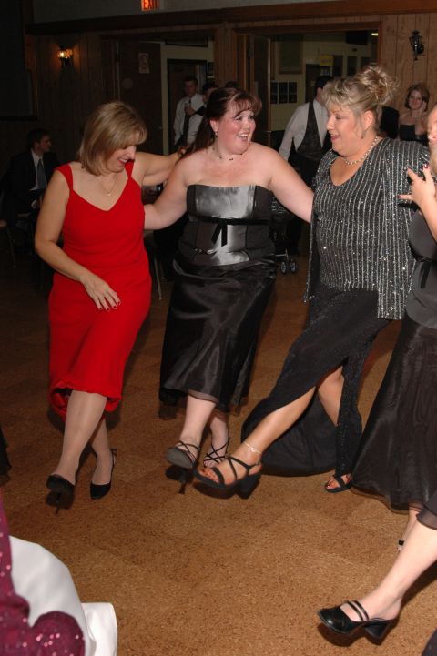 1985 Ford Crown Victoria LTD - Three women in dresses are dancing together at a wedding reception.