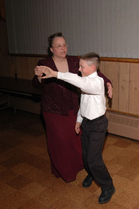 1985 Ford Crown Victoria LTD - A woman and a young boy are shown dancing in a room with wood-paneled walls.