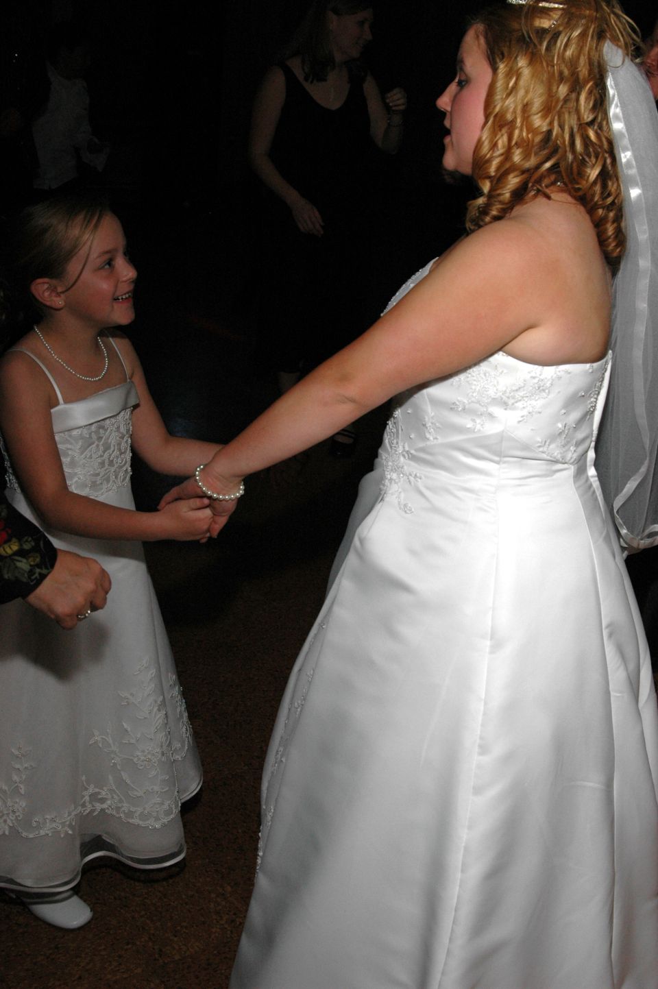 Bride and flower girl holding hands at a wedding reception