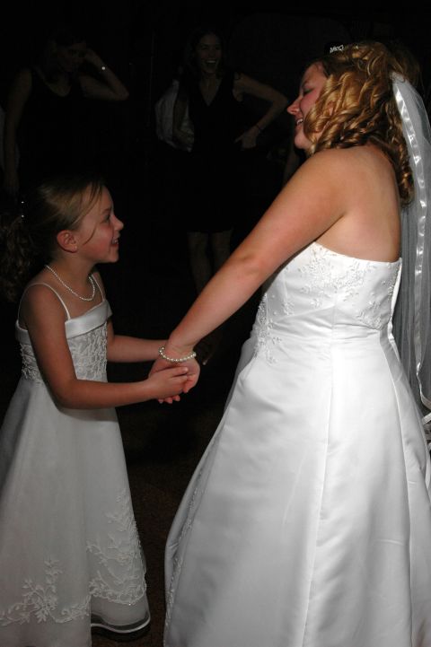Bride and flower girl holding hands and dancing