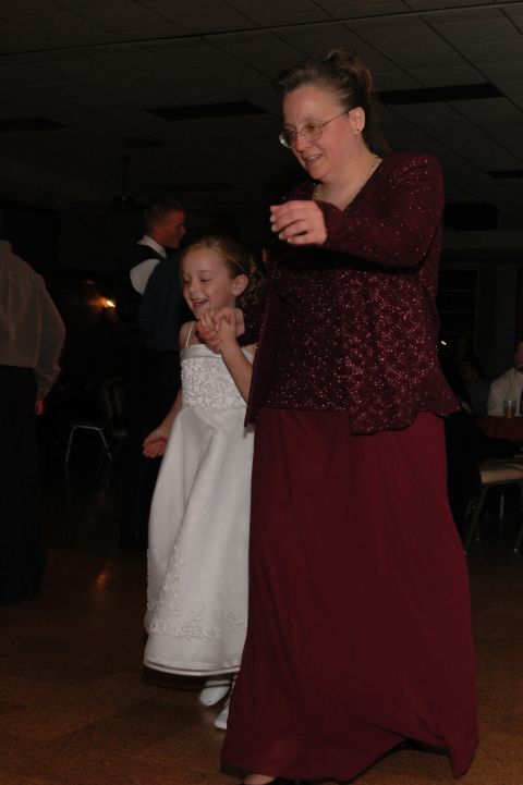 woman in a maroon dress and a young girl in a white dress holding hands and dancing