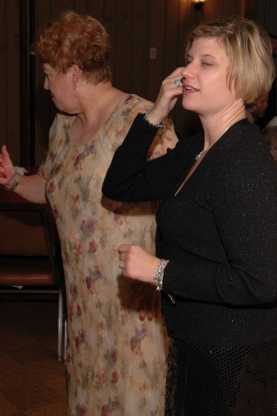 Woman in floral dress and woman in black sweater at an indoor event