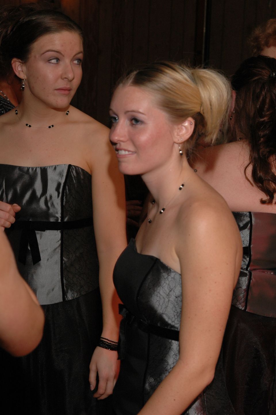 Two women in formal dresses, one looking to the side