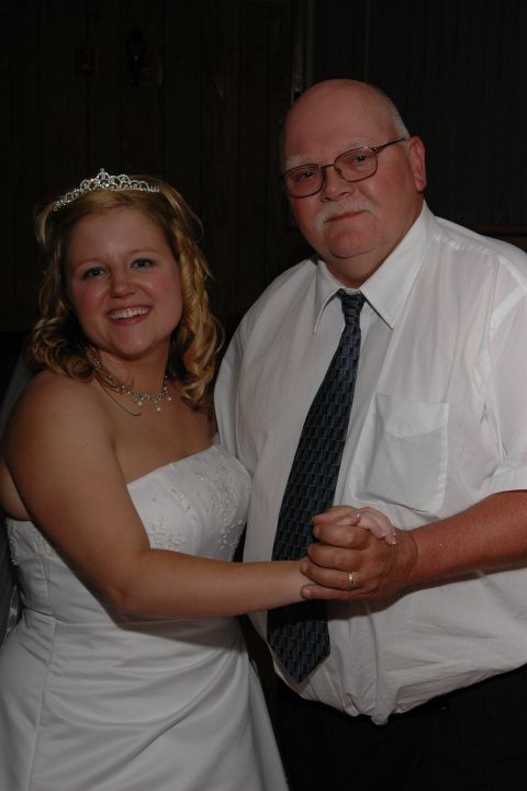 Bride in a white wedding dress and tiara dances with a man in a white shirt and tie