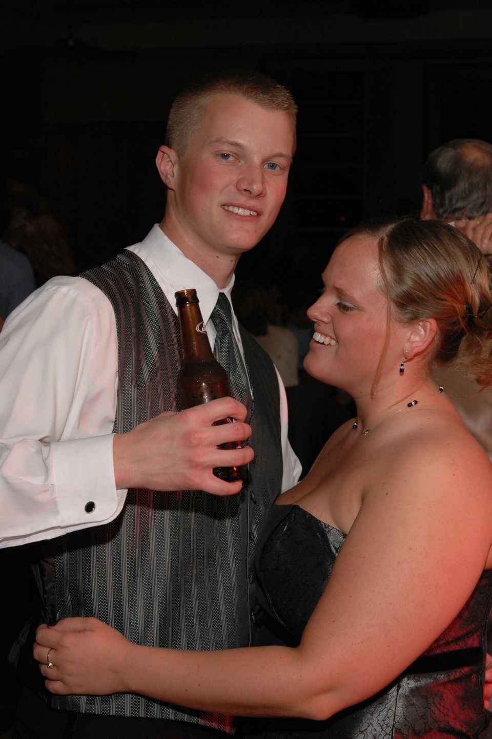 Couple dancing at a wedding, man holds a beer bottle