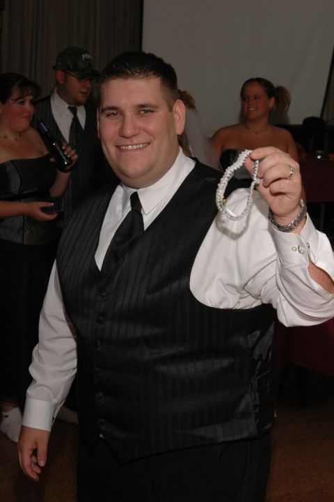 Man in tuxedo holding a garter at a wedding reception