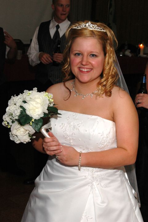 Bride in a white strapless wedding dress holding a bouquet of white roses