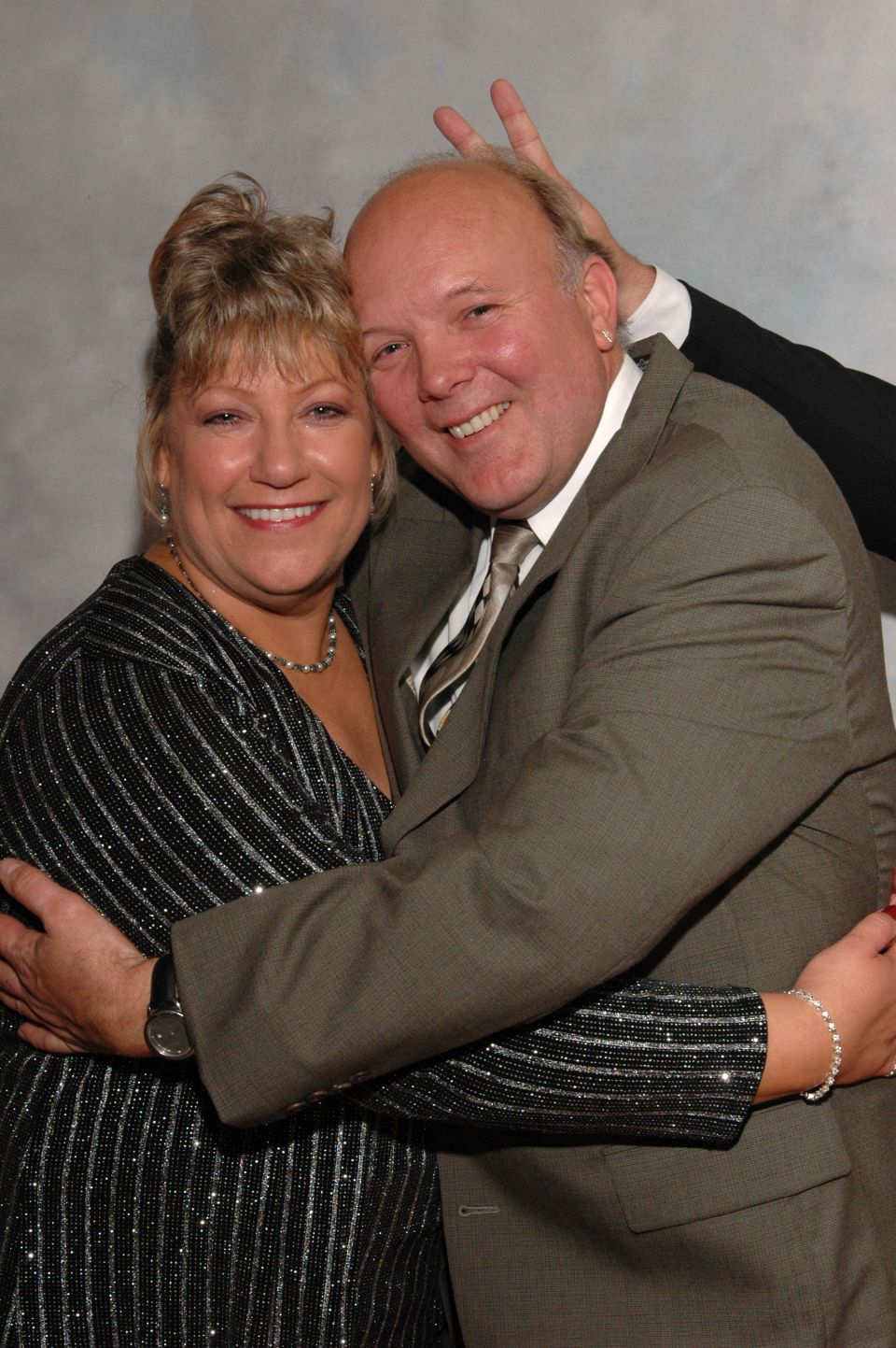 Couple hugging, man making bunny ears behind woman's head