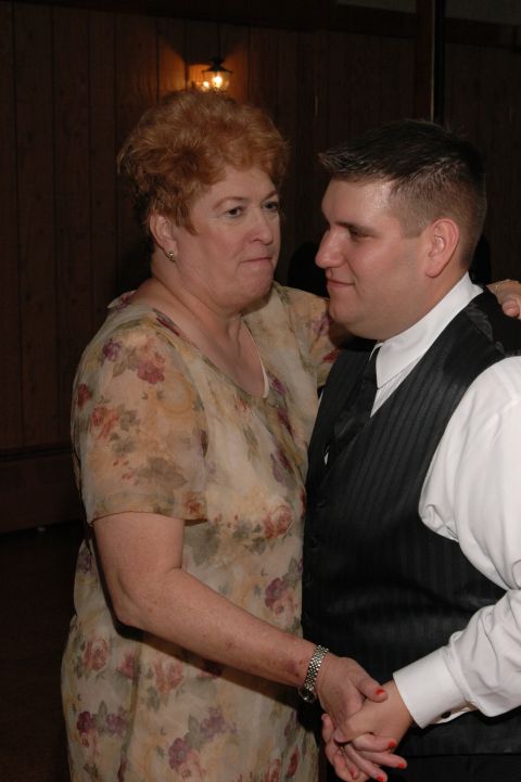 Woman in floral dress and man in vest holding hands while dancing