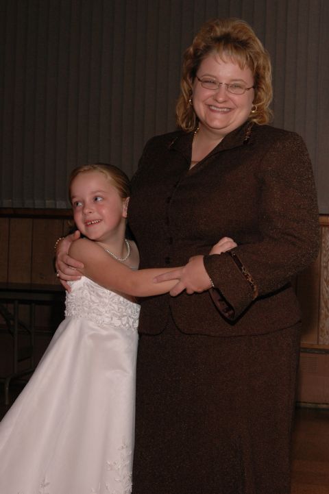 Woman and young girl in formal attire, holding hands