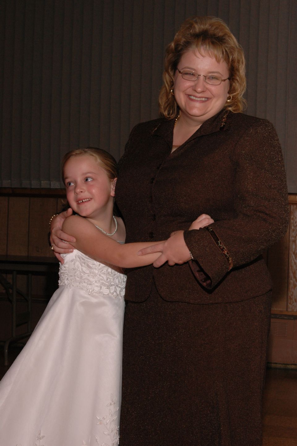 Woman and young girl in formal attire, holding hands