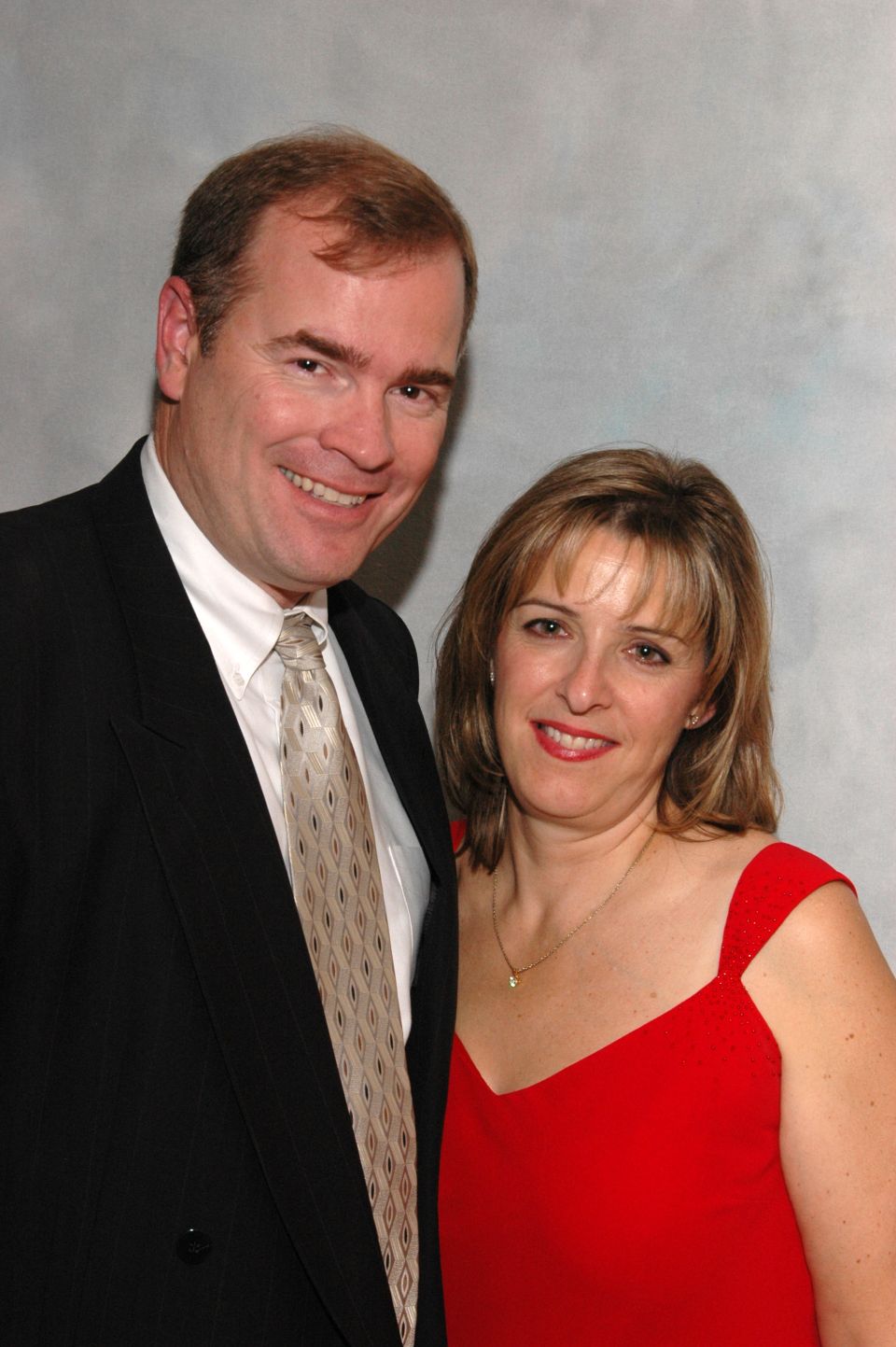 Man in suit and tie with woman in red dress smiling