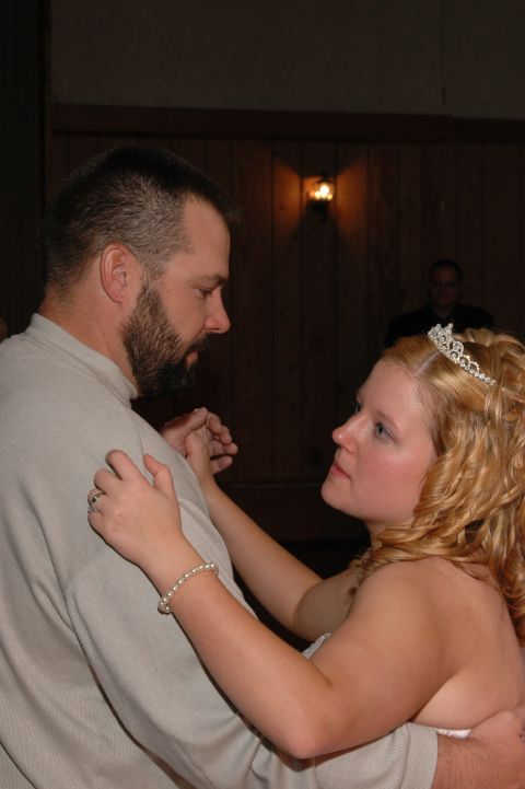 Man and woman in wedding attire dancing, with another person in the background