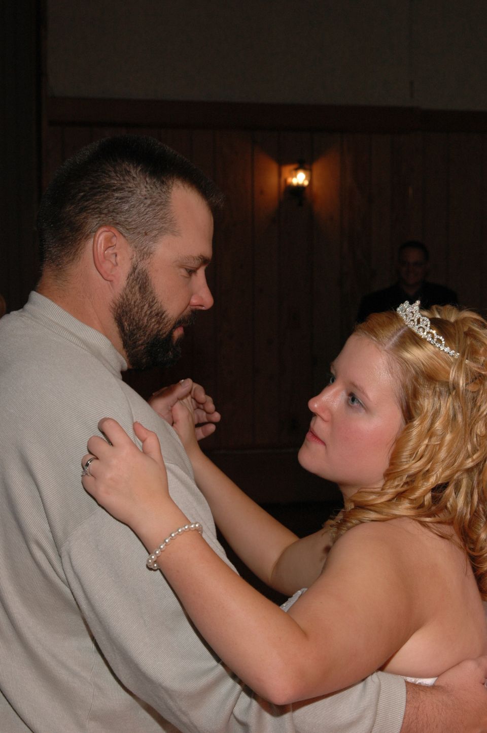 Man and woman in wedding attire dancing, with another person in the background