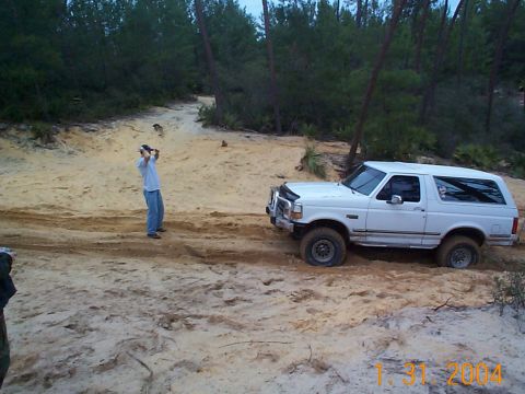 1992 Ford Bronco - White 1992 Ford Bronco navigates a sandy off-road path.