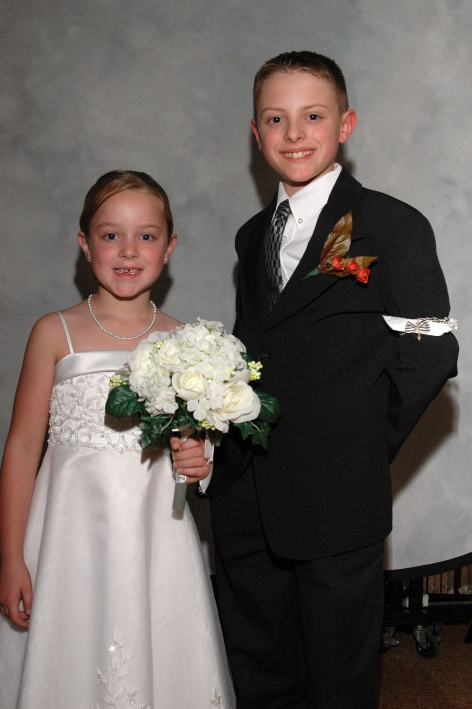Young boy in a suit and young girl in a white dress holding flowers