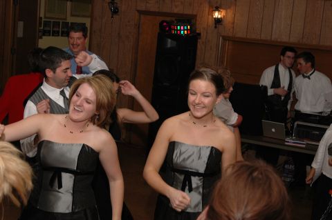 people dancing at a party with a DJ booth in the background