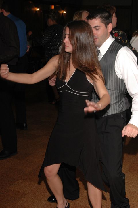 People dancing at an event. A woman in a black dress dances with a man in a vest