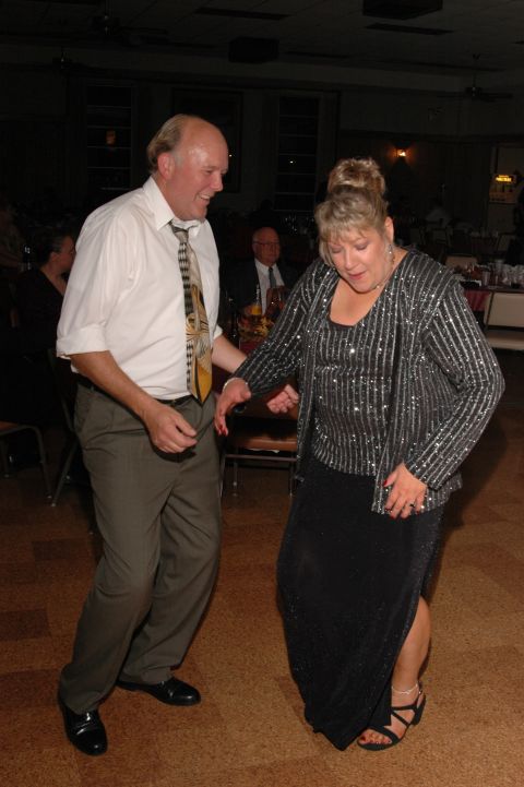 Couple dancing at a formal event. Man in white shirt and tie, woman in sparkly top and black dress