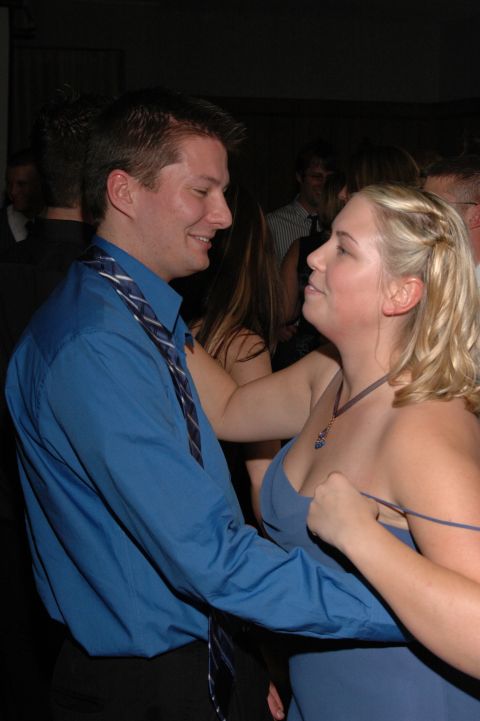 Man in blue shirt and tie dances with woman in blue dress