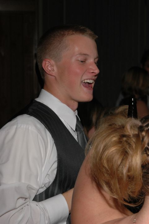 Man in a white shirt and grey vest laughs at a formal event