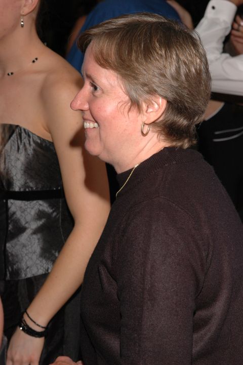 Woman smiling in profile, wearing a dark sweater and hoop earrings