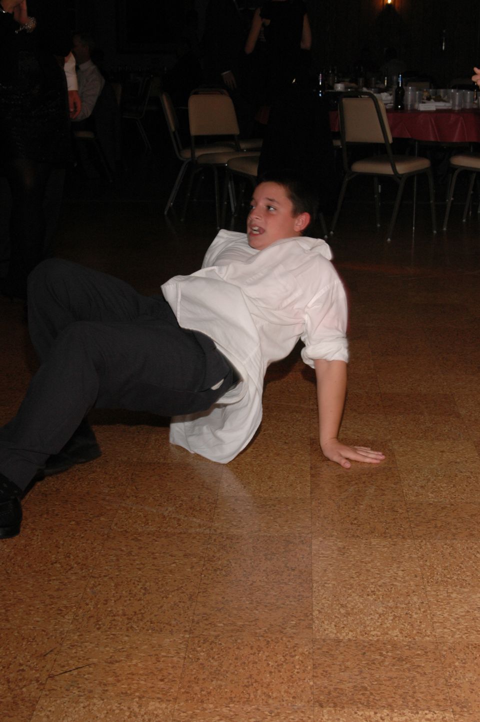Kid in white shirt and dark pants on the floor, looking up