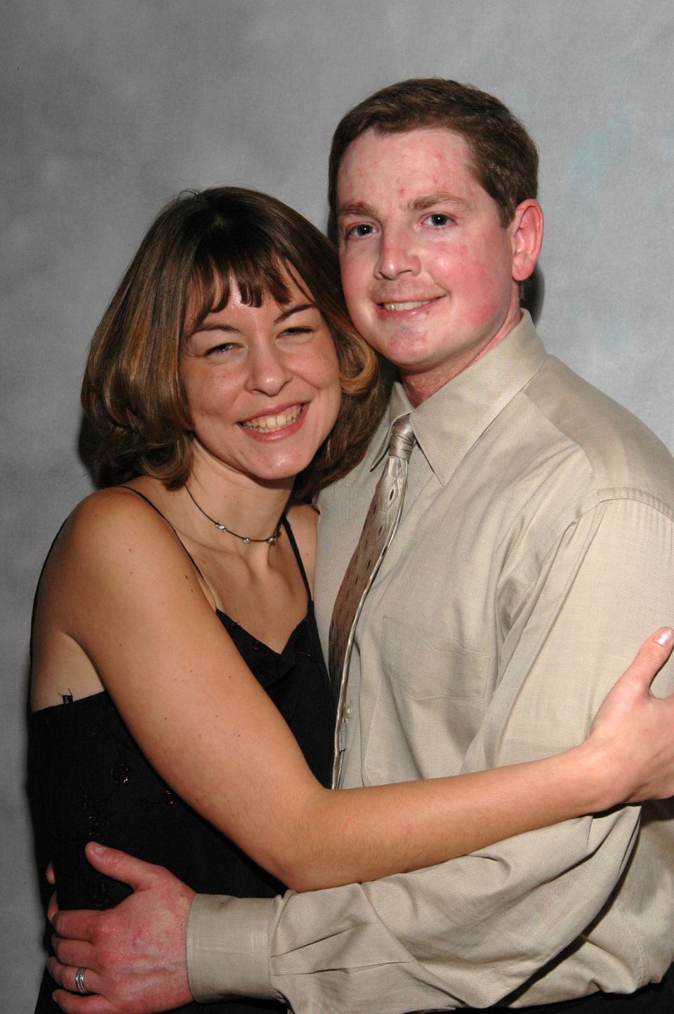 Couple embracing, woman in black dress, man in tan shirt and tie