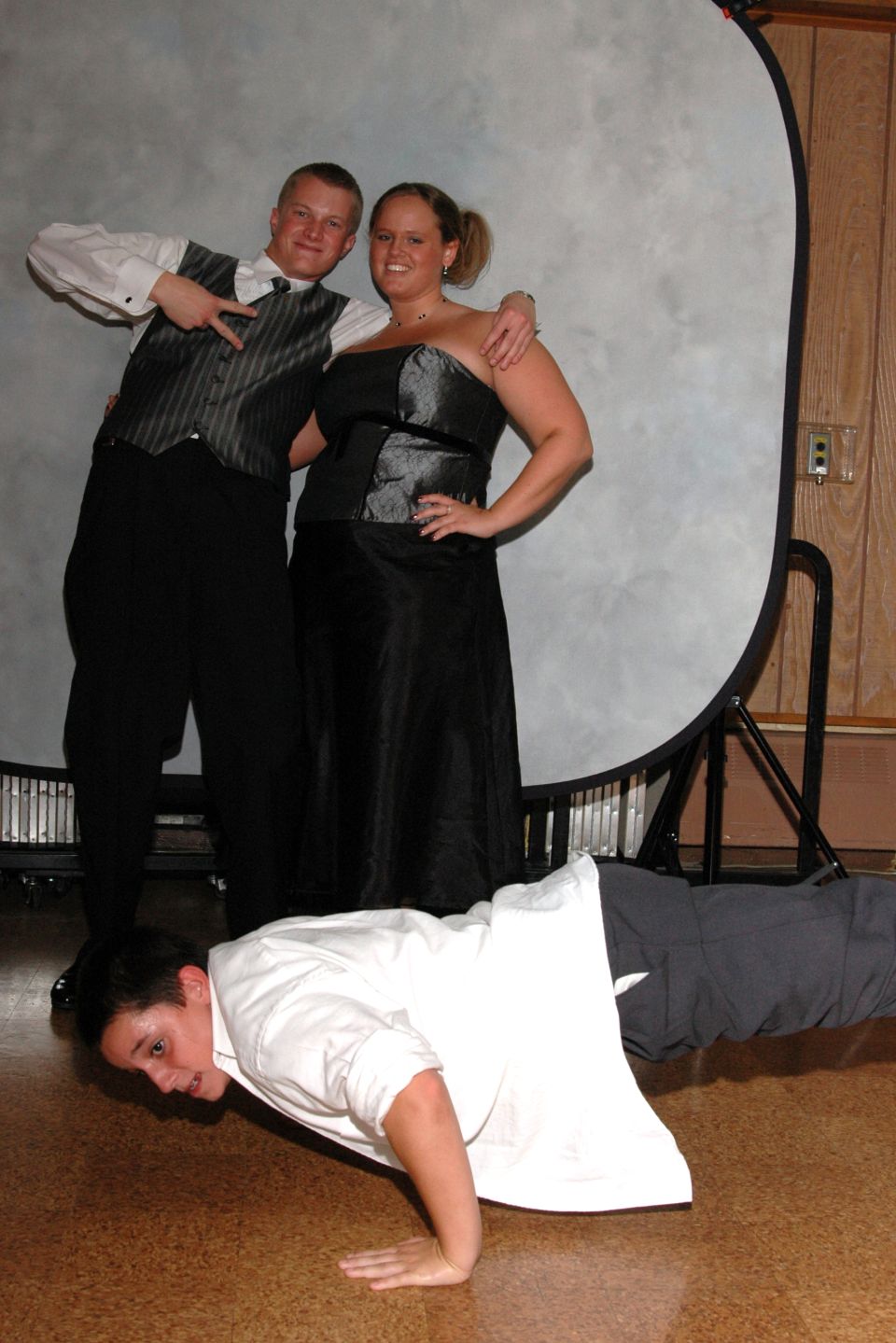 Three people posing for a photo, one doing a push-up on the floor