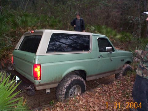 1992 Ford Bronco - A 1992 Ford Bronco is stuck in the mud with people around it.