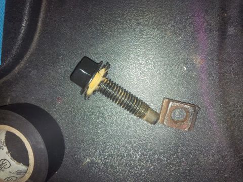 1978 Ford Bronco - A bolt assembly and electrical tape are shown on a dark, textured surface.