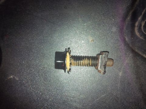 1978 Ford Bronco - A close-up view of a bolt and nut assembly, a black cap and a serrated washer, against a textured dark surface.