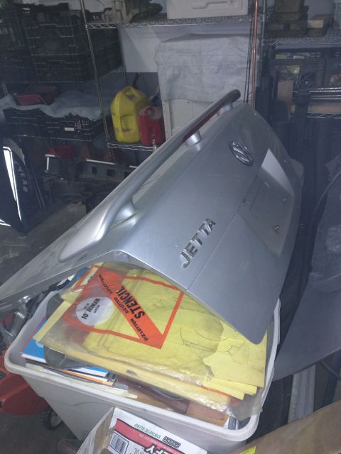 2002 Volkswagen Jetta - Trunk lid identified as 'JETTA' with a Volkswagen badge, placed on a bin of stencils.