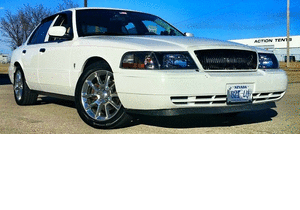 2000 Mercury Grand Marquis - A white 2000 Mercury Grand Marquis is parked on a dirt lot under a clear blue sky.