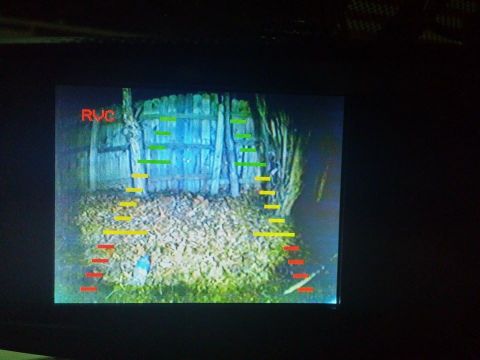 2000 Mercury Grand Marquis - The backup camera display shows the RVC designation and parking guide lines overlaid on a backyard scene with a wooden fence.