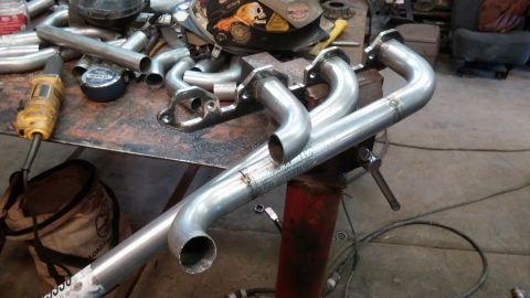 1995 Ford Bronco - Custom exhaust headers are laid out on a workbench in a workshop setting.