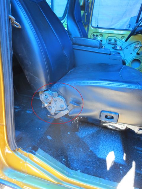 1978 Ford Bronco - Close-up of a vehicle's interior, focusing on the seat adjustment mechanism and black vinyl seats.
