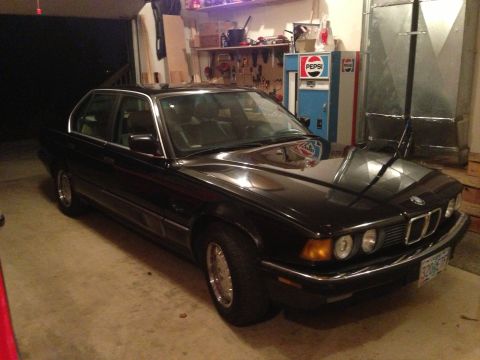 1988 BMW 7 Series - A black 1988 BMW 7 Series sedan is parked indoors, showing its distinctive grille and headlights.