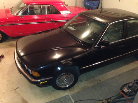 1988 BMW 7 Series - A black 1988 BMW 7 Series sedan is parked next to a red classic car.