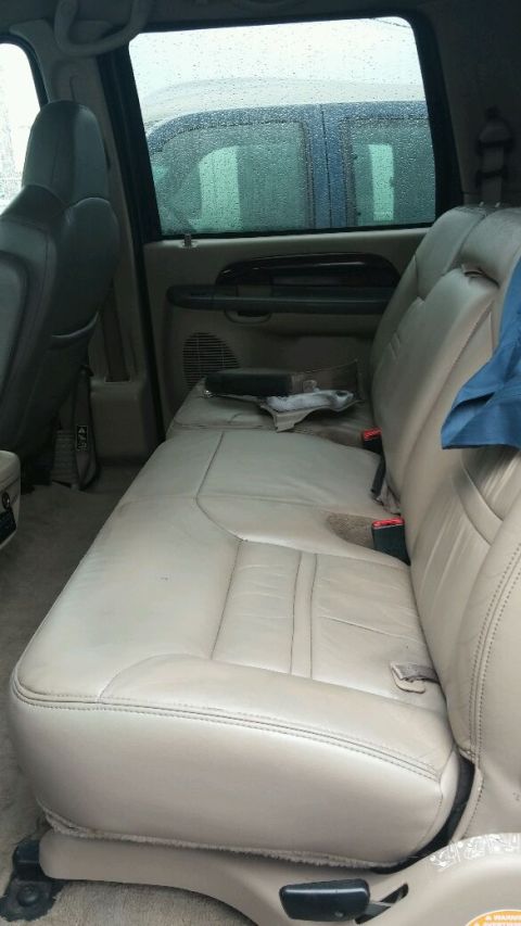 2003 Ford Excursion - Interior view of a vehicle showing tan leather seats and a glimpse of another vehicle outside.
