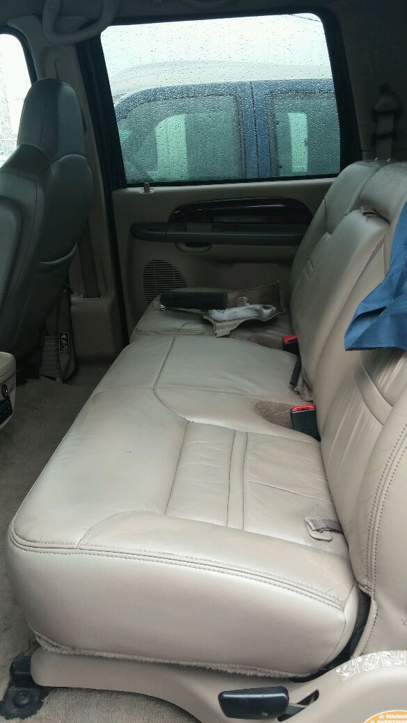 Tan leather seats in a vehicle interior, with a blue SUV visible through the window
