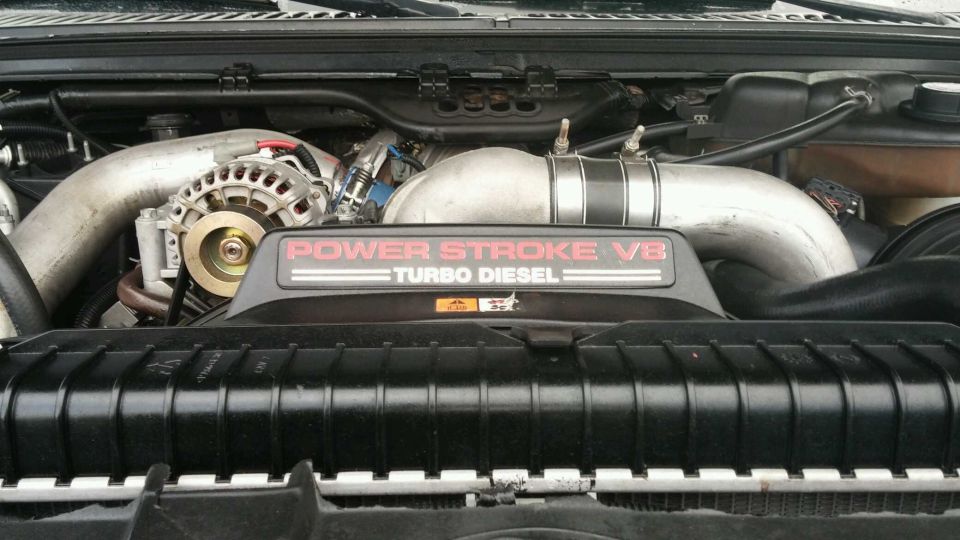 Engine bay with "POWER STROKE V8 TURBO DIESEL" cover. Alternator visible