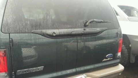 2003 Ford Excursion - The rear of a dark green 2003 Ford Excursion is visible, parked next to another vehicle.