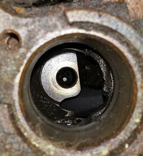 1995 Ford Bronco - A close-up view of an engine part, showing oil and debris within its housing.