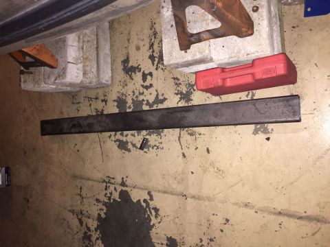 1994 Ford Bronco - Tools and a metal bar are laid out on a stained concrete floor, suggesting a work in progress.