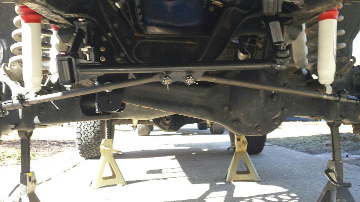 Undercarriage of a vehicle on jack stands, showing suspension and differential