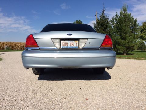 2003 Ford Crown Victoria - Rear view of a silver 2003 Ford Crown Victoria parked outdoors with a cornfield in the background.
