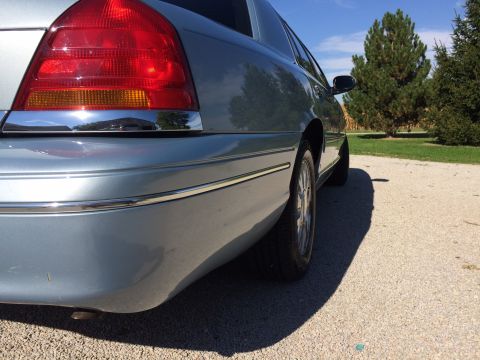 2003 Ford Crown Victoria - Rear quarter view of a light blue 2003 Ford Crown Victoria sedan parked on a gravel surface.