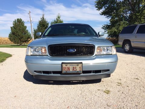 2003 Ford Crown Victoria - Front view of a blue 2003 Ford Crown Victoria parked outdoors with another vehicle in the background.