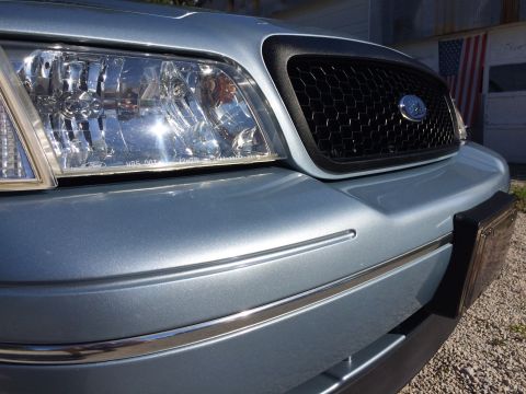 2003 Ford Crown Victoria - Front view of a light blue 2003 Ford Crown Victoria, showing the grille and headlight detail.